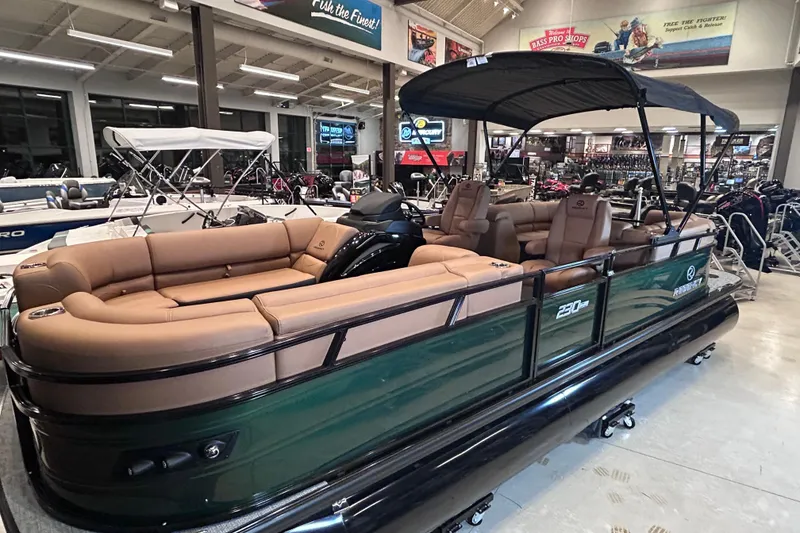 Slide: The Image of 2026 Regency 230 DL pontoon boat with tan seating, displayed in a showroom. - 3