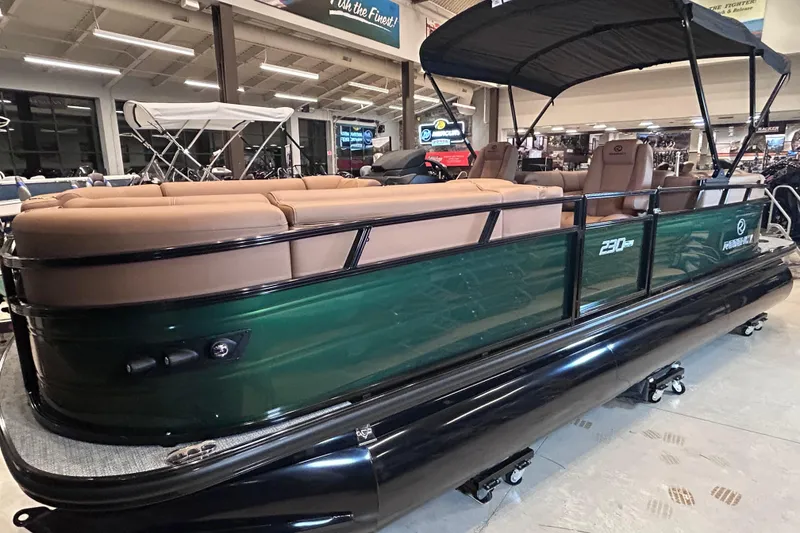 Slide: The Image of 2026 Regency 230 DL pontoon boat with tan seating and black canopy in showroom. - 4