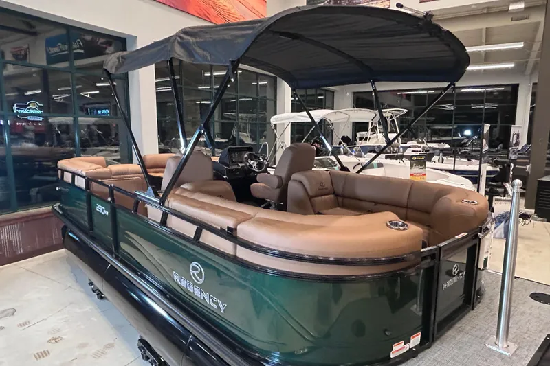 Slide: The Image of 2026 Regency 230 DL pontoon boat with tan seating and black canopy in showroom. - 6