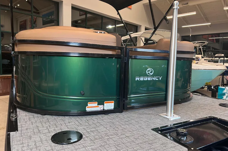 Slide: The Image of 2026 Regency 230 DL pontoon boat with green exterior and tan seating in showroom. - 8