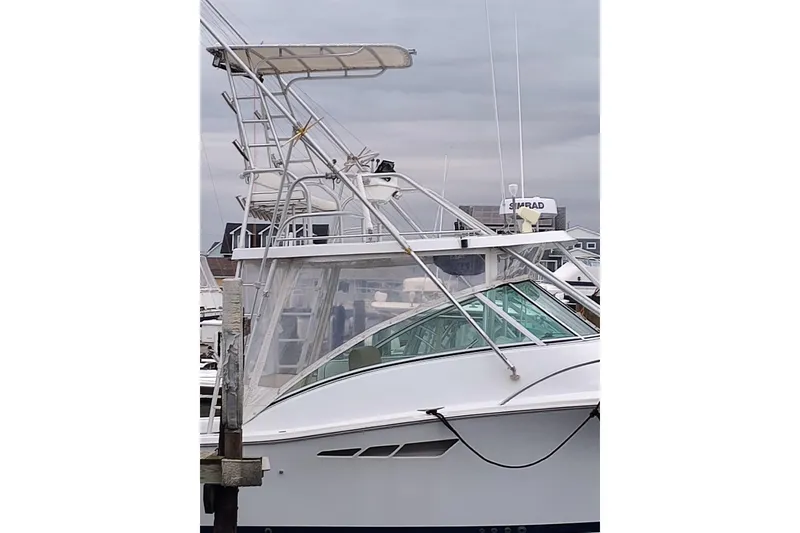 Slide: The Image of 1998 Luhrs 36 SX Open boat docked, featuring a tower and clear enclosure. - 13