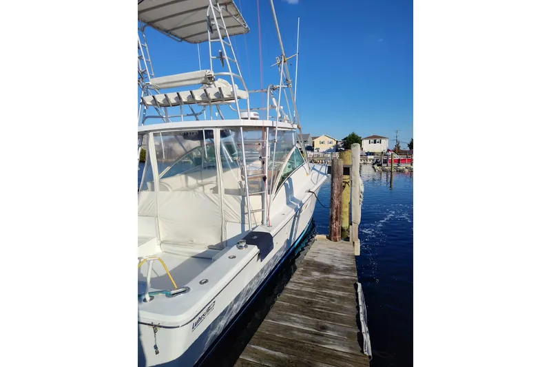 Slide: The Image of 1998 Luhrs 36 SX Open boat docked at marina under clear blue sky. - 3