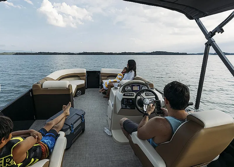 Slide: The Image of 2025 Lowe SS230WT pontoon boat on a lake with passengers relaxing. - 12