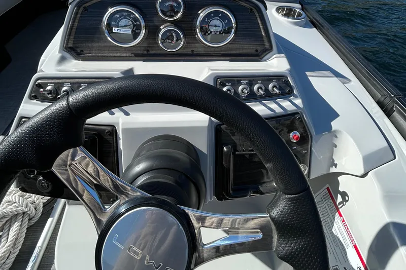 Slide: The Image of Steering wheel and dashboard of 2025 Lowe SS230WT boat on water. - 3