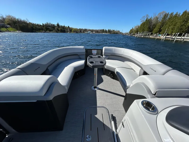 Slide: The Image of 2025 Lowe SS230WT pontoon boat interior with spacious seating on a scenic lake. - 4
