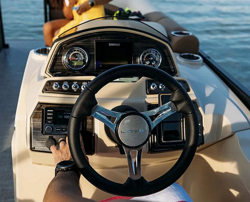 Slide: The Image of 2025 Lowe SS230WT boat dashboard with steering wheel and control panel on water. - 8