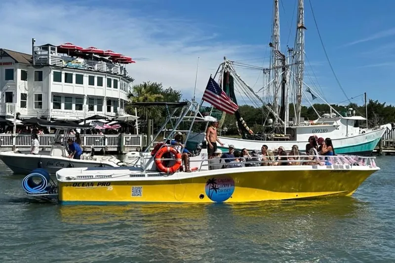 Slide: The Image of Yellow OceanPro 35 CWS boat with passengers, docked near waterfront buildings, 2021 model. - 12