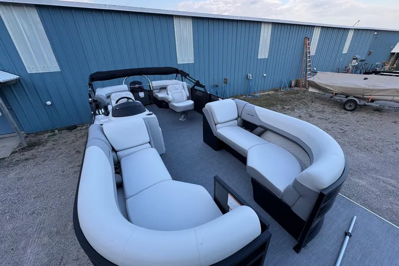 Slide: The Image of 2025 Lowe SS230WV pontoon boat with spacious seating, parked near a blue building. - 3