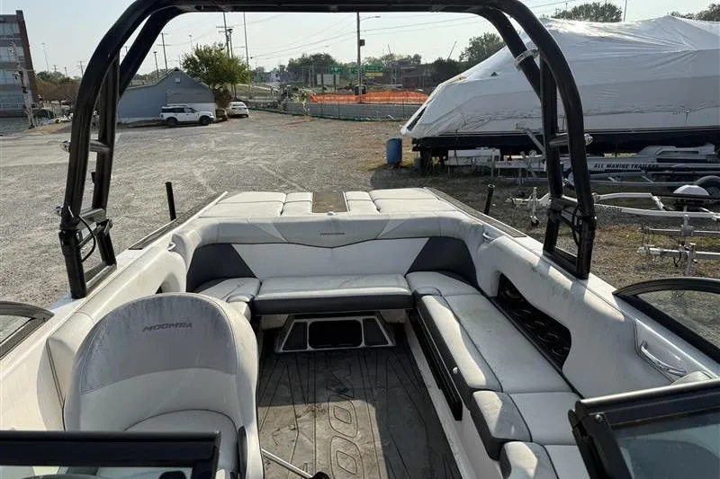 Slide: The Image of 2016 Moomba Craz boat interior with white seating and black accents in a marina setting. - 4