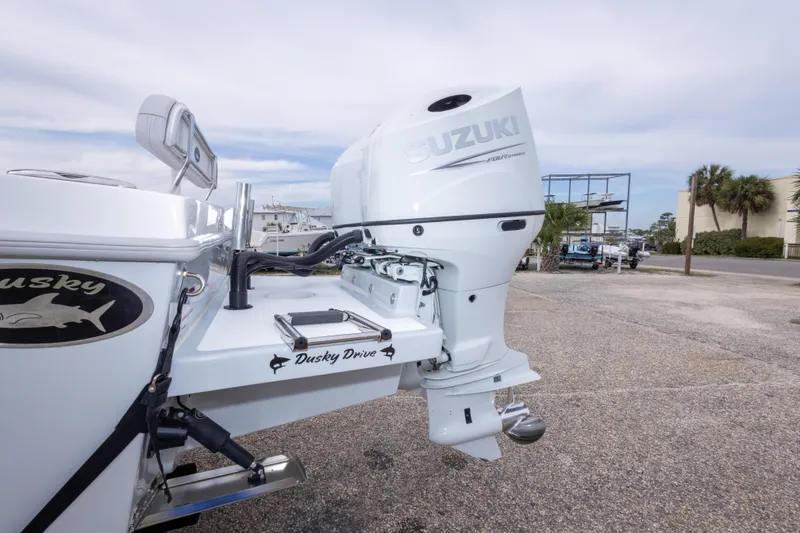 Slide: The Image of 2023 Dusky 252 Open Fisherman with Suzuki outboard motor in a marina setting. - 12