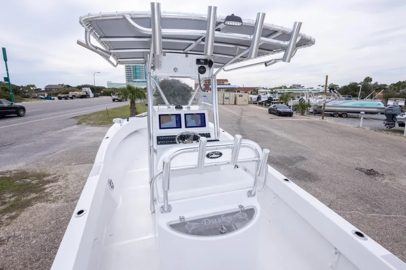 Slide: The Image of 2023 Dusky 252 Open Fisherman boat with dual screens and T-top, parked near a road. - 13