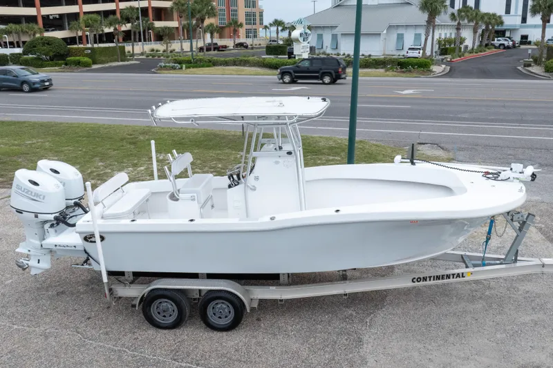 Slide: The Image of 2023 Dusky 252 Open Fisherman boat on trailer, featuring twin Suzuki engines. - 33
