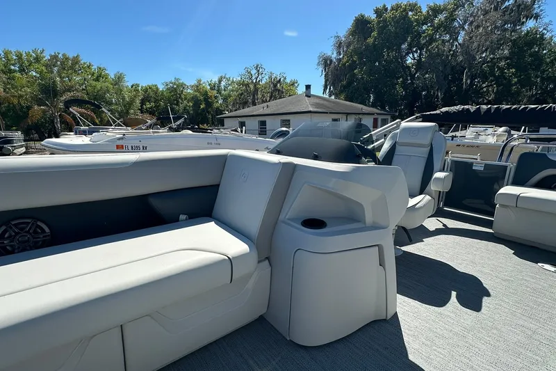 Slide: The Image of 2026 Sweetwater SW2086CPSE pontoon boat interior with seating and console, surrounded by trees. - 10