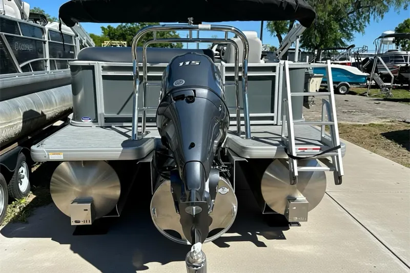 Slide: The Image of 2026 Sweetwater SW2086CPSE pontoon boat with outboard motor and ladder, parked on concrete. - 43