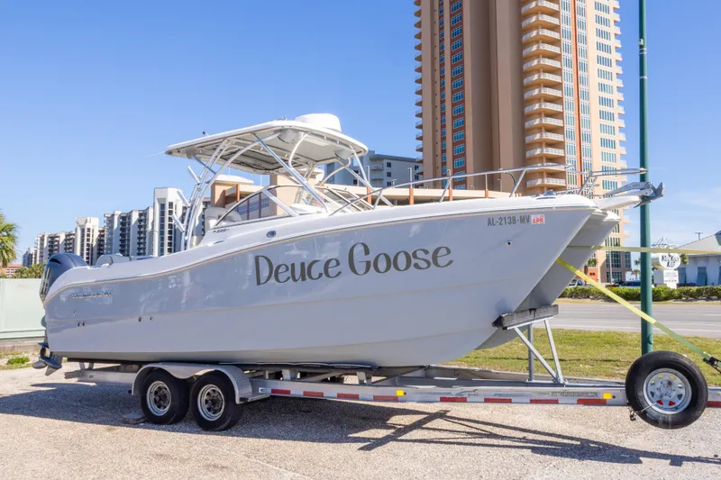 Slide: The Image of 2016 World Cat 255 DC boat named "Deuce Goose" on trailer, urban backdrop. - 11