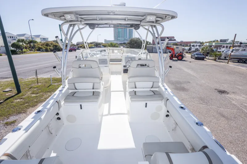 Slide: The Image of 2016 World Cat 255 DC boat interior with seating and helm, parked near a marina. - 23