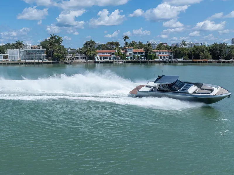 Slide: The Image of 2024 CNM CONTINENTAL 54 SuperSport yacht cruising on a sunny day near waterfront homes. - 14