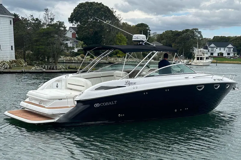 The Image of 2008 Cobalt 323 boat on calm water, surrounded by trees and houses. - 0