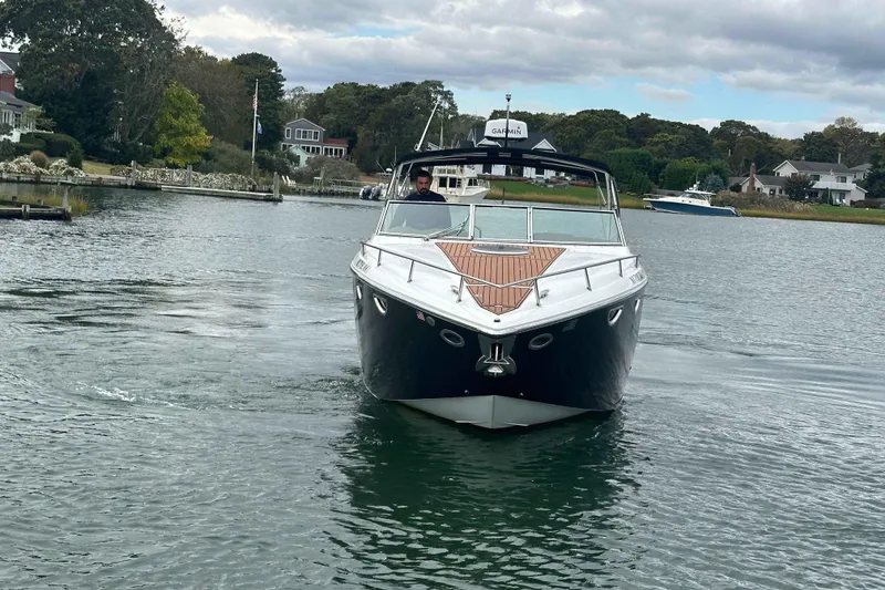 Slide: The Image of 2008 Cobalt 323 boat cruising on a scenic waterway with houses in the background. - 4