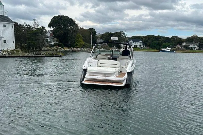 Slide: The Image of 2008 Cobalt 323 boat cruising on a calm lake near shoreline houses. - 5