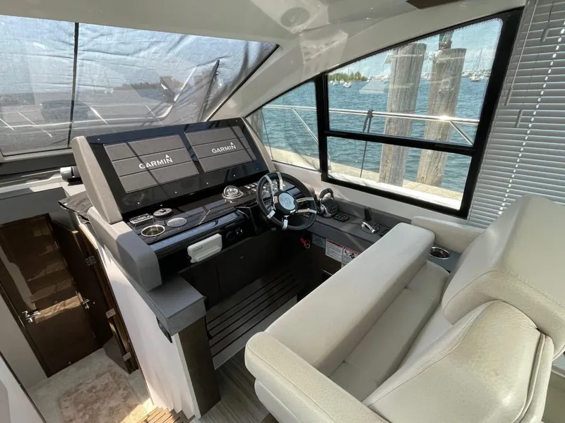 Slide: The Image of 2019 Cruisers 50 Cantius helm with Garmin displays, luxurious seating, and waterfront view. - 15