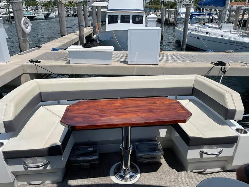 Slide: The Image of 2019 Cruisers 50 Cantius yacht with elegant seating and wooden table at marina. - 8