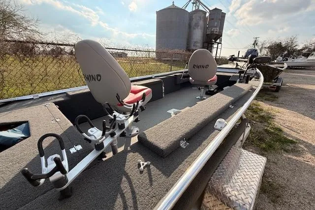 Slide: The Image of 2022 Rhino V Pro Stick boat with dual seats, rod holders, and rural backdrop. - 6