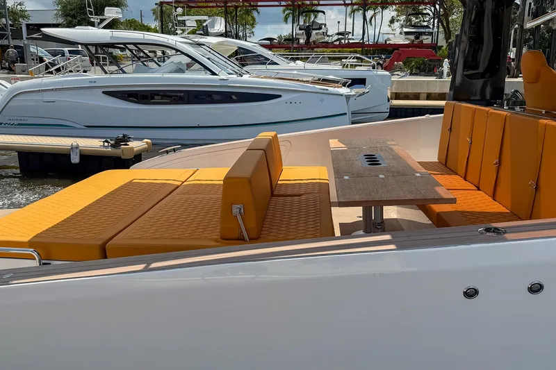 Slide: The Image of 2024 Tesoro T40 yacht with orange seating and wooden table, docked beside another boat. - 14