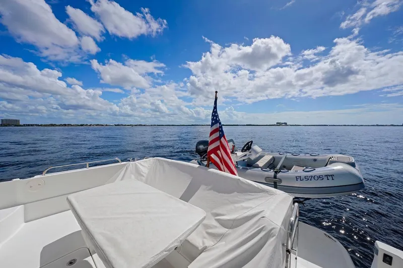 Slide: The Image of 2019 Sabre 45 Salon Express yacht with American flag and inflatable boat on open water. - 56