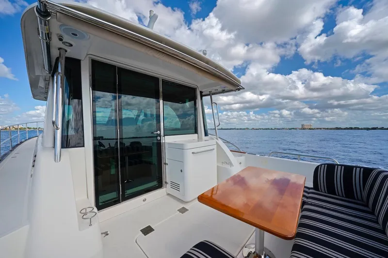 Slide: The Image of 2019 Sabre 45 Salon Express yacht deck with table, striped seating, and ocean view. - 61