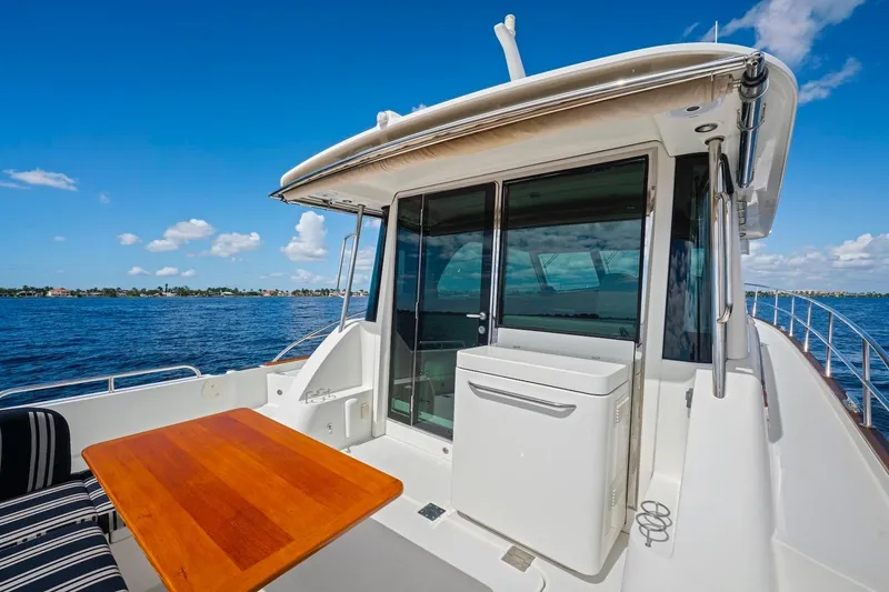 Slide: The Image of 2019 Sabre 45 Salon Express yacht deck with wooden table, ocean view, and clear blue sky. - 63