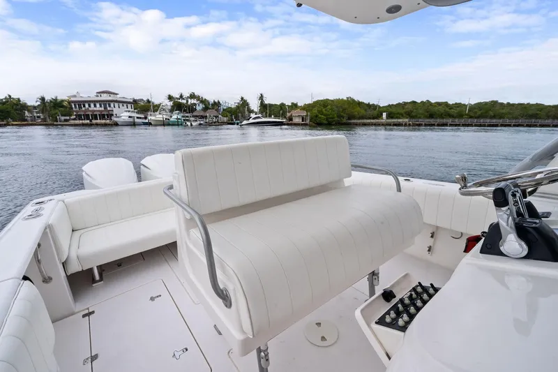 Slide: The Image of 2011 Intrepid 370 Cuddy boat interior with white seating, docked near waterfront homes. - 9