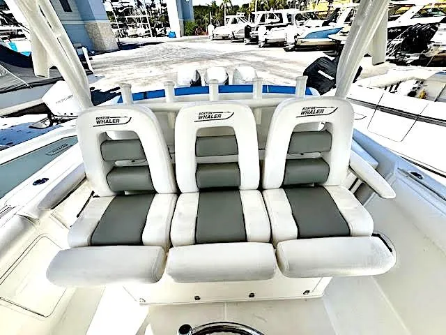 Slide: The Image of 2016 Boston Whaler 350 Outrage boat seating, featuring three cushioned seats in a marina setting. - 16