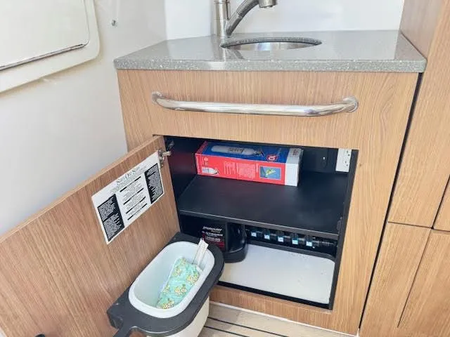 Slide: The Image of Interior of 2016 Boston Whaler 350 Outrage showing a sink and open cabinet storage. - 39