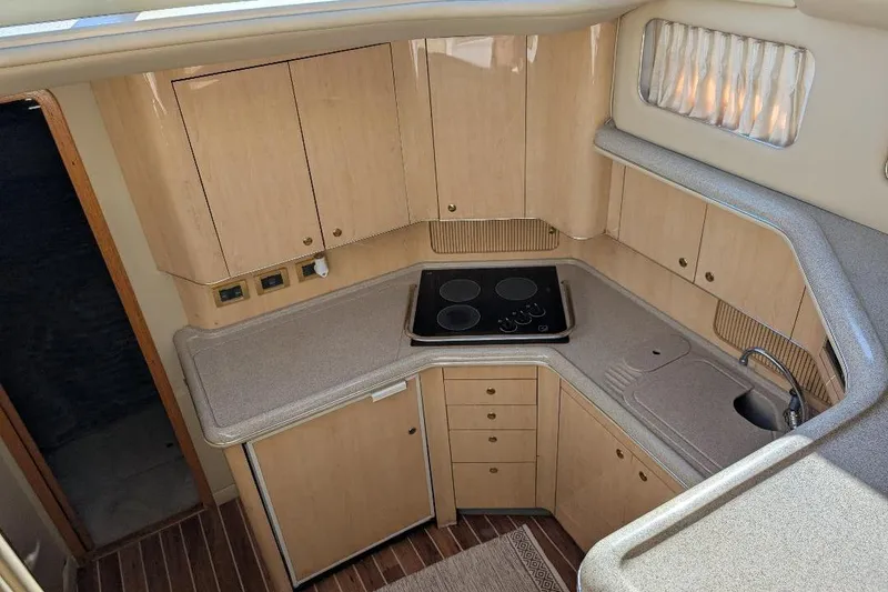 Slide: The Image of 2000 Sea Ray 420 Aft Cabin yacht kitchen with stove, sink, and wooden cabinetry. - 11