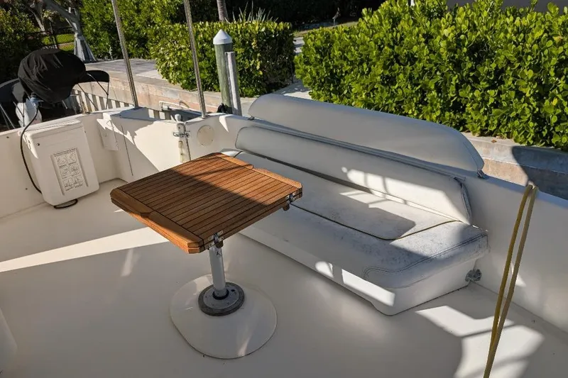 Slide: The Image of 2000 Sea Ray 420 Aft Cabin boat interior with wooden table and cushioned seating. - 9