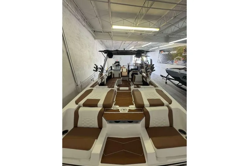 Slide: The Image of 2026 Malibu Wakesetter 24 MXZ boat interior with brown and white seating in showroom. - 3