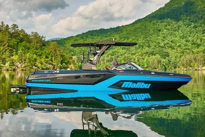 Slide: The Image of Manufacturer Provided Image: 2026 Malibu Wakesetter 24 MXZ boat on a serene lake with lush green hills. - 9