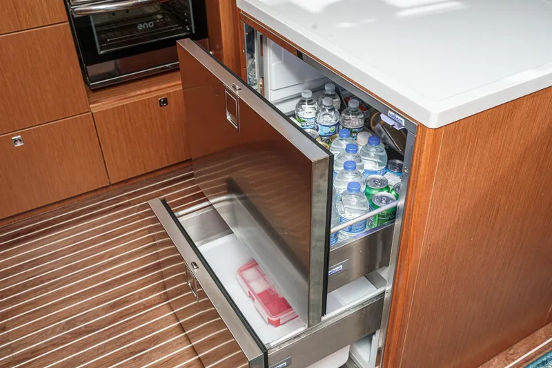 Slide: The Image of Modern Bavaria C50 yacht kitchen with open drawer fridge, stocked with bottled water and drinks. - 39