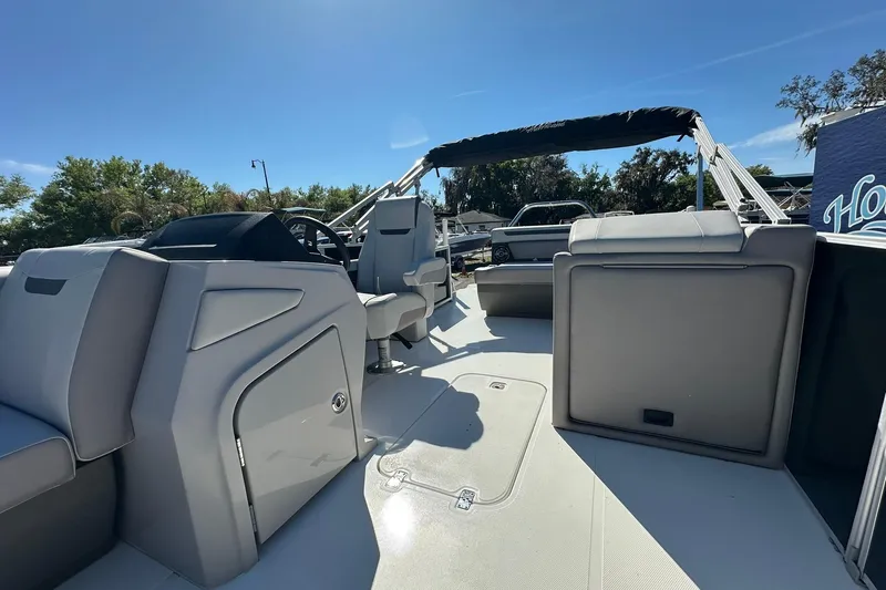 Slide: The Image of 2026 Sweetwater FD2260RE3 pontoon boat interior with seating and helm under sunny sky. - 12