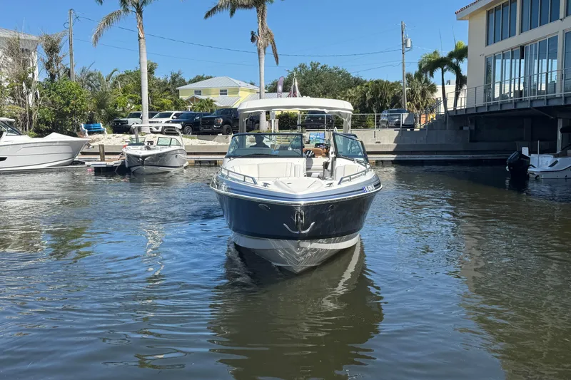Slide: The Image of 2021 Formula 330 Crossover Bowrider OB on calm water near docked boats and palm trees. - 5
