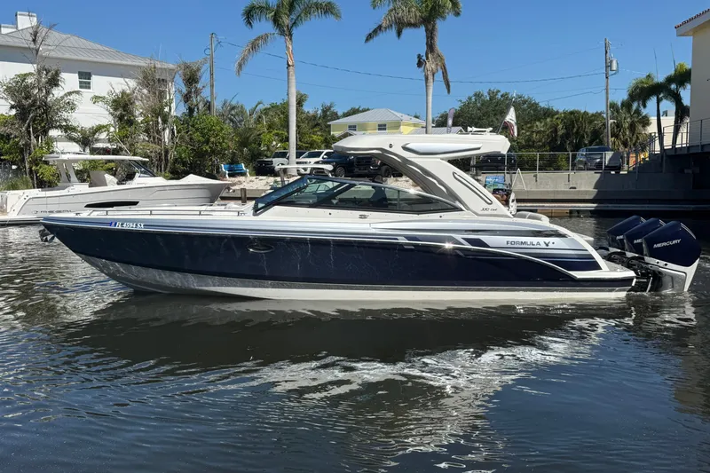 Slide: The Image of 2021 Formula 330 Crossover Bowrider OB on calm water, surrounded by palm trees. - 6