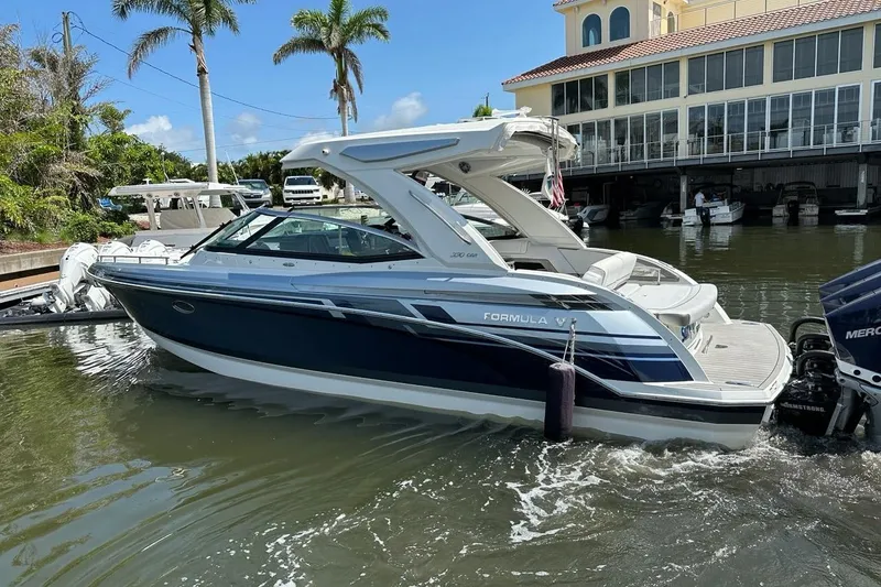 Slide: The Image of 2021 Formula 330 Crossover Bowrider OB in marina, palm trees and building in background. - 8