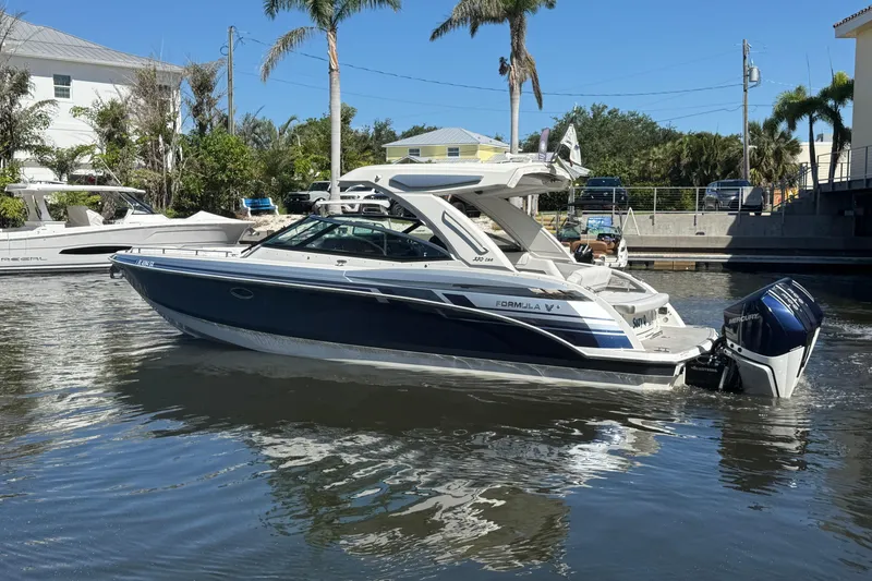 Slide: The Image of 2021 Formula 330 Crossover Bowrider OB on calm water, surrounded by palm trees. - 9