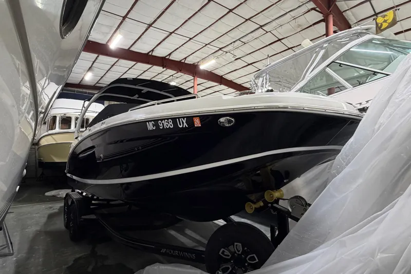 Slide: The Image of 2024 Four Winns HD5 boat in storage, black hull, indoor facility. - 2