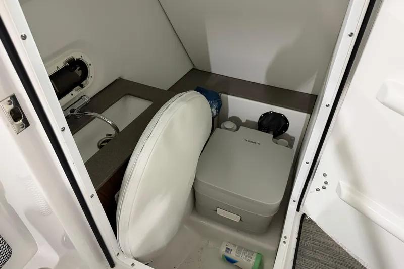 Slide: The Image of 2024 Four Winns HD5 boat interior with compact bathroom and portable toilet. - 39