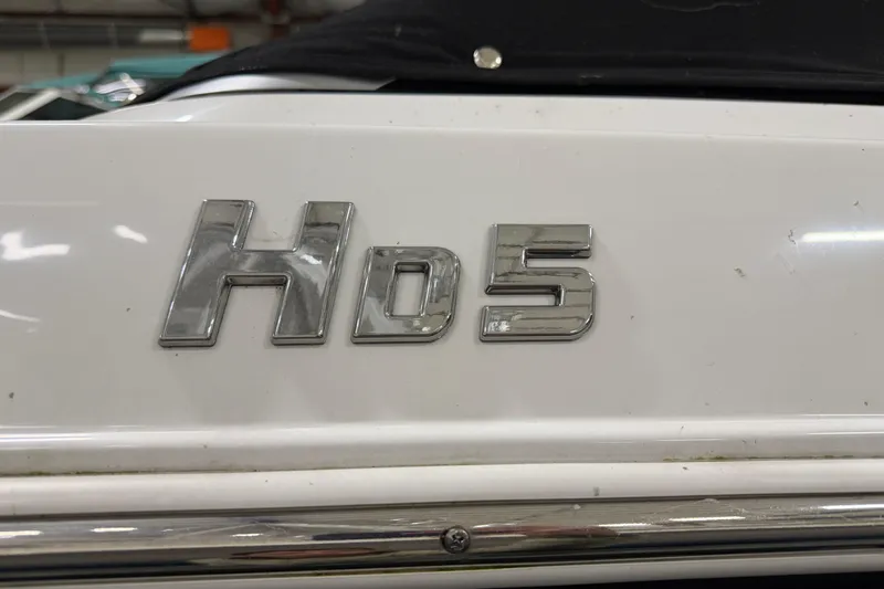 Slide: The Image of 2024 Four Winns HD5 boat emblem in chrome on white surface. - 58