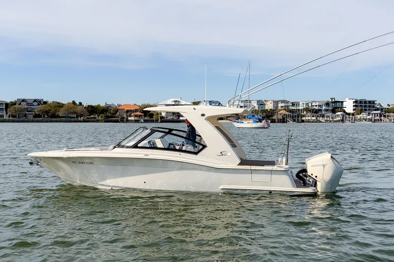 The Image of 2023 Scout 277 Dorado boat on calm water near coastal homes. - 0