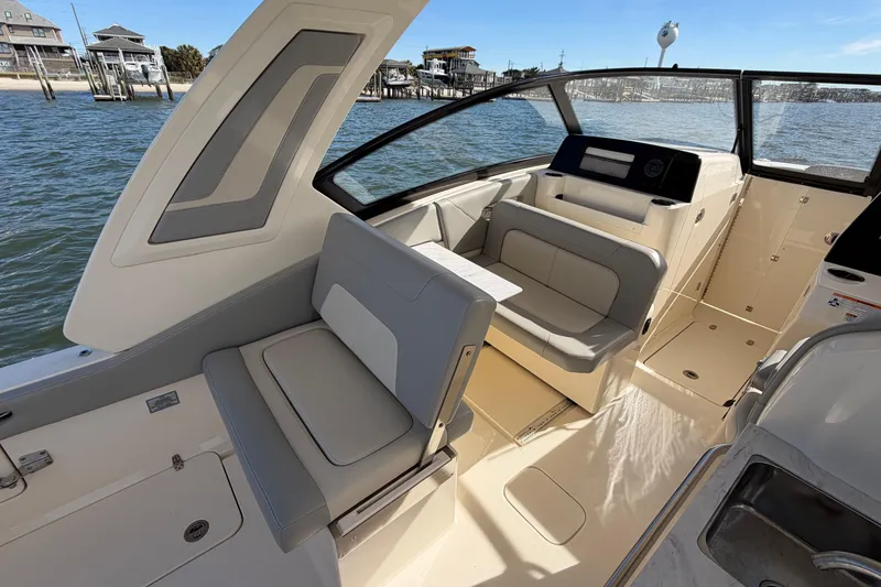 Slide: The Image of 2023 Scout 277 Dorado boat interior with seating and helm, docked by the water. - 16