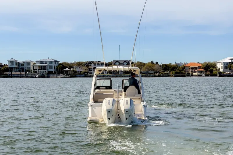 Slide: The Image of 2023 Scout 277 Dorado boat cruising on a calm waterway near waterfront homes. - 2